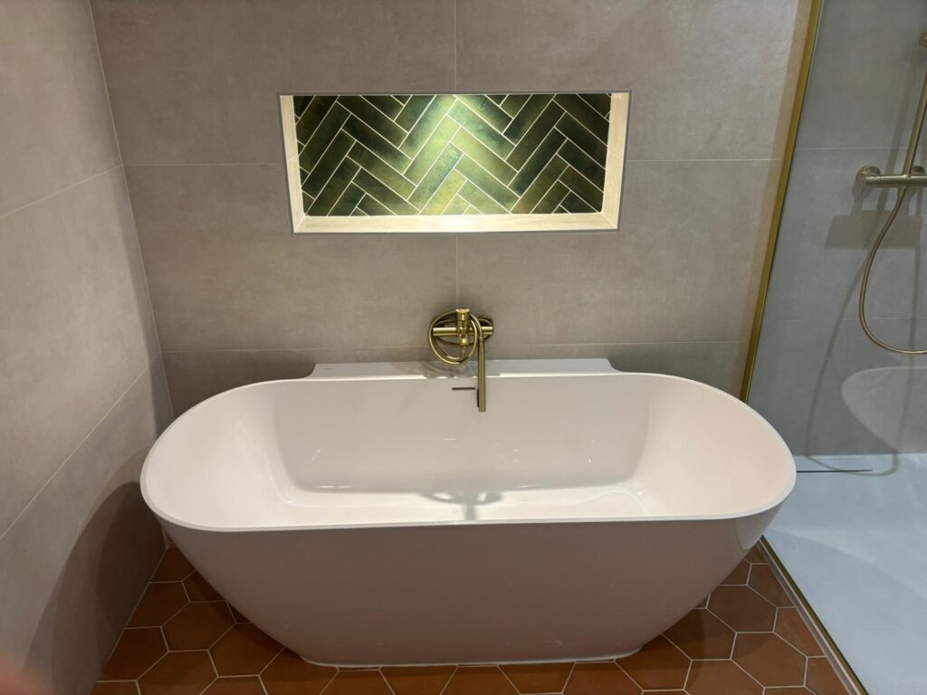 Baignoire Moderne, Niche Carrelée Vert Émeraude, Laiton Baignoire îlot moderne blanche sous niche carrelée vert émeraude à chevrons, robinetterie laiton, sol carreaux hexagones terre cuite.