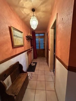 Couloir rustique terracotta avec banc bois et lustre vintage.