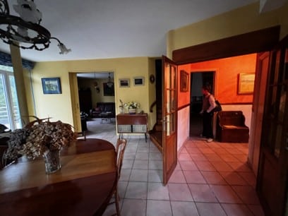 Salle à manger rustique ouvrant sur un salon et un couloir chaleureux.