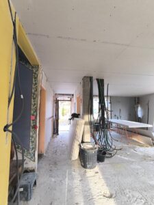 Chantier de rénovation avec plafond en placo, faisceaux de câbles électriques et cloisons en cours de montage.