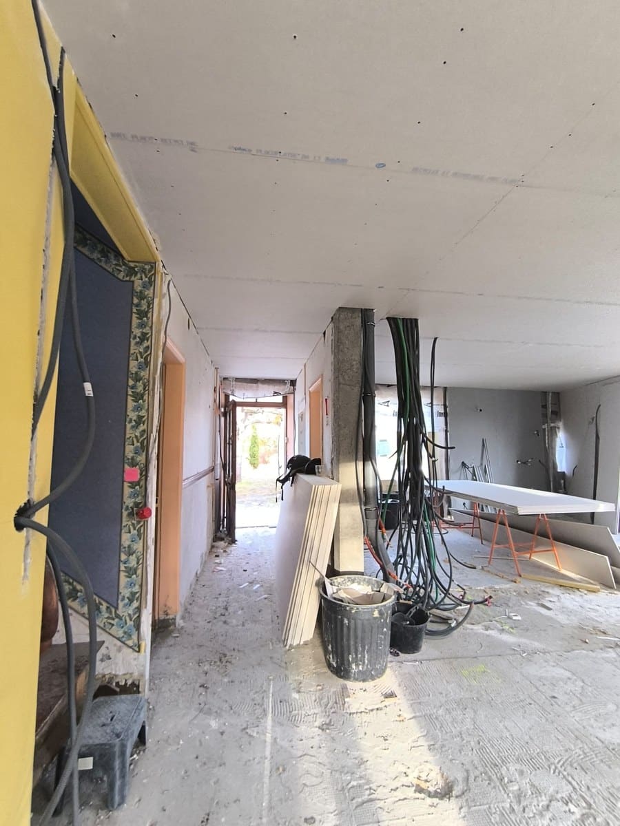 Chantier de rénovation avec plafond en placo, faisceaux de câbles électriques et cloisons en cours de montage.