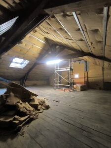 Combles en rénovation : isolation sous toiture, échafaudage central et charpente bois apparente.